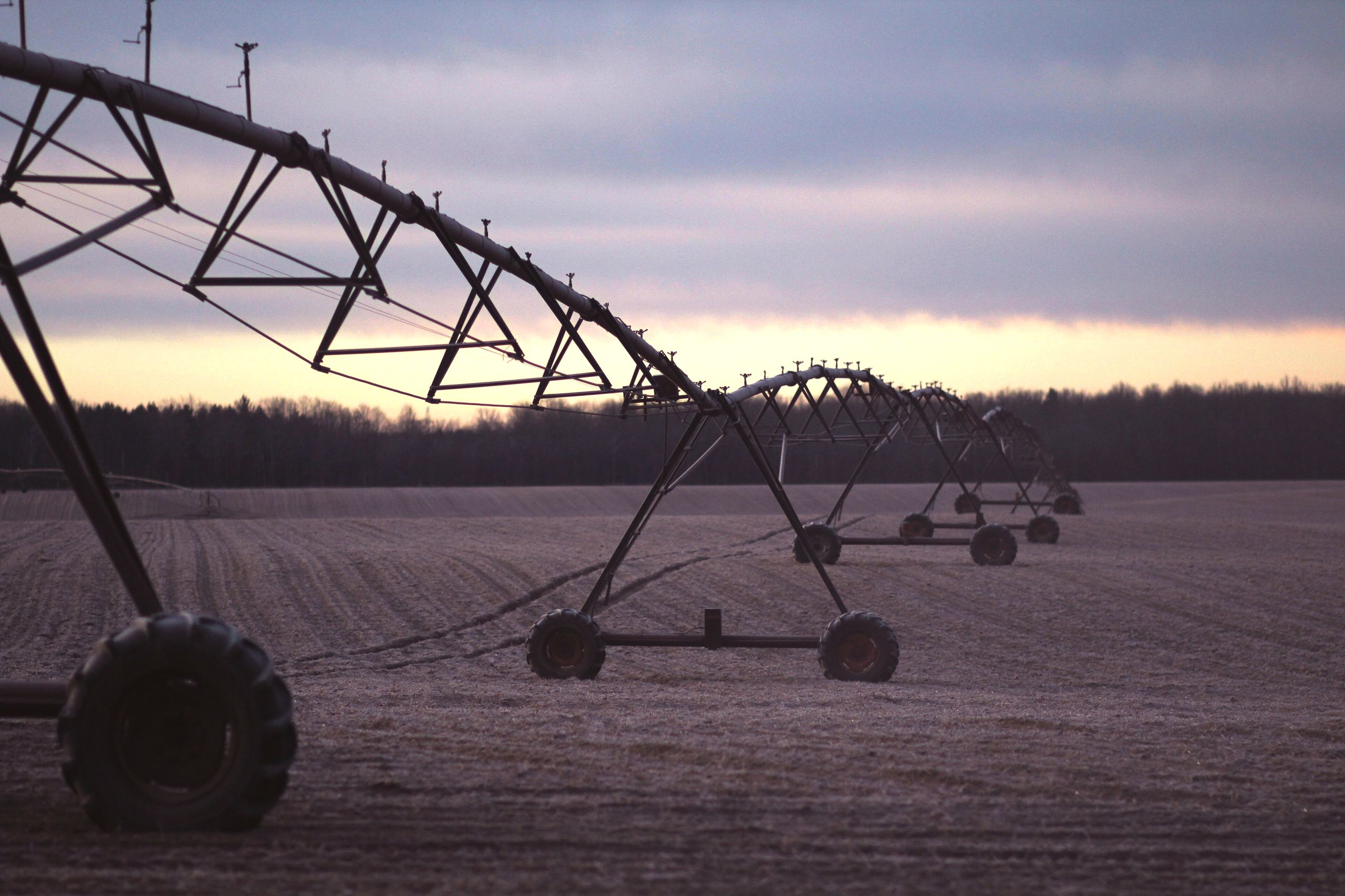 Center pivot irrigation equipment standing over a field at dusk